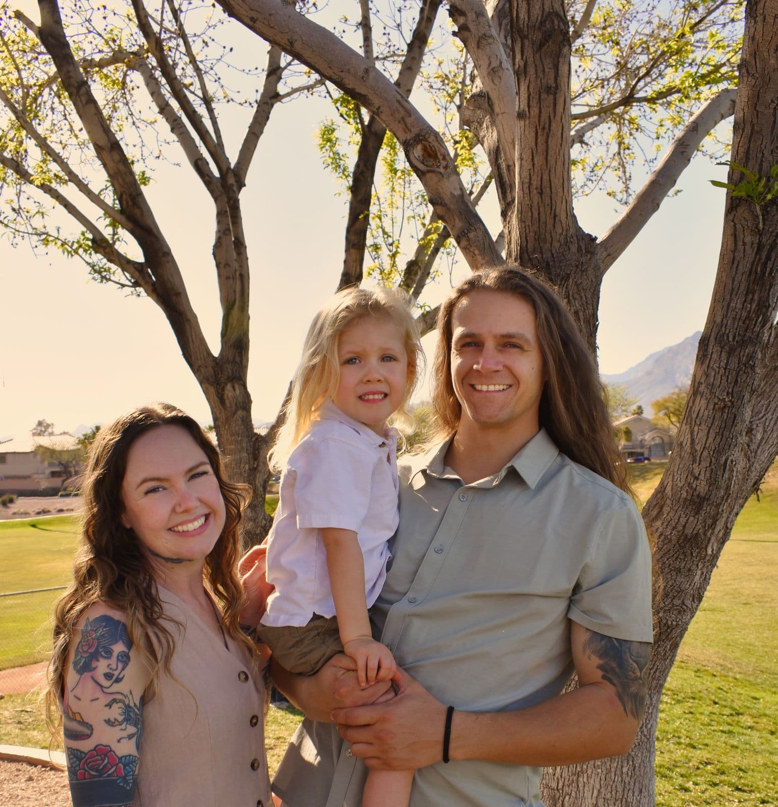 A mother, father and young daughter photographed together beneath a tree in a Las Vegas park